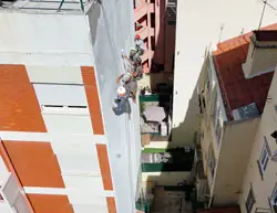 Técnico de alpinismo industrial a realizar restauração de fachada por rapel com aplicação de capoto em Lisboa